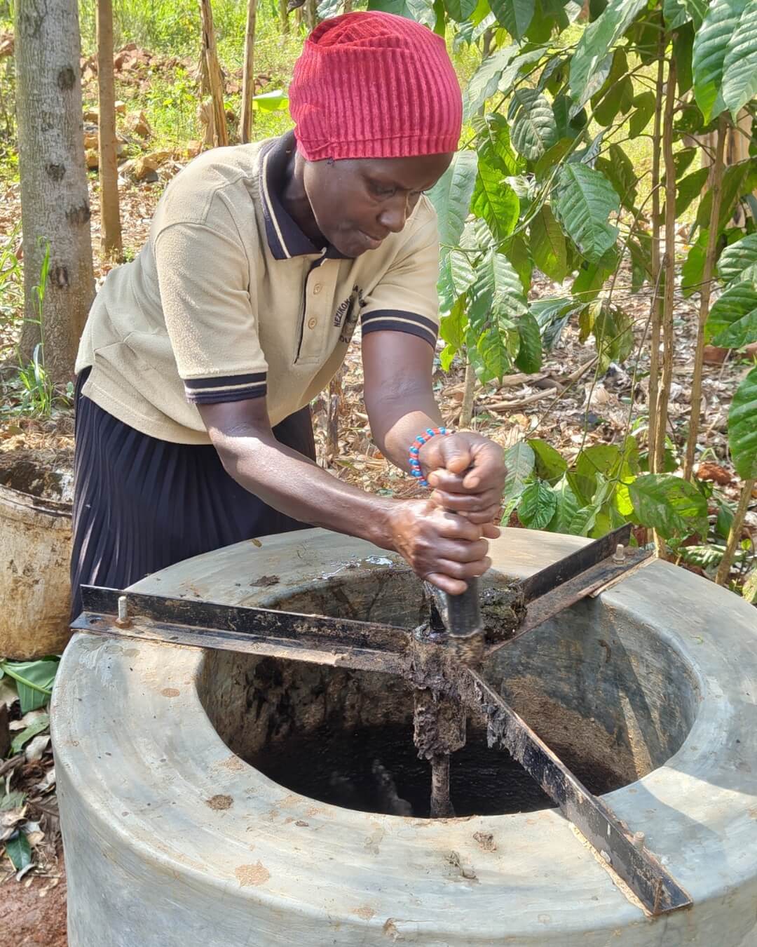 Über einem Betontrichter ist ein metallenes Drehkreuz mit einem Griff in der Mitte installiert, den eine Frau mit beiden Händen umfasst.