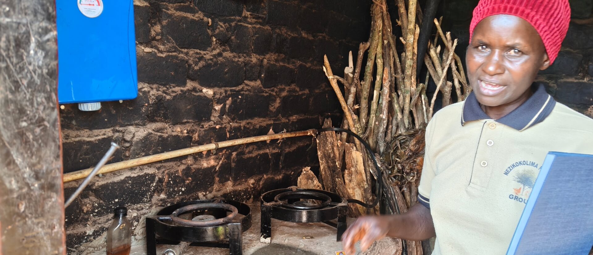 Vor einer Wand aus schwarzen Ziegeln steht eine Frau neben zwei Gaskochern.