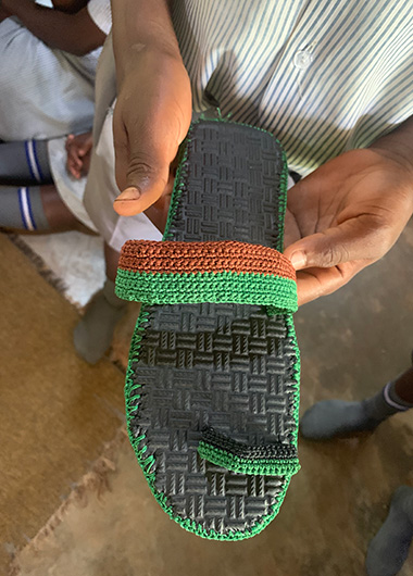 Stolz präsentieren die Schüler*innen der Nambeeta School in Uganda ihre selbstgefertigten Sandalen.