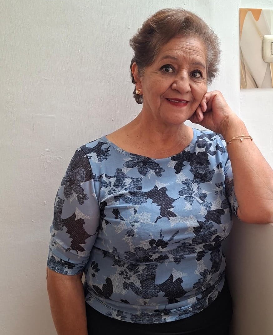 Eine Frau steht an eine Wand gelehnt und lächelt in die Kamera.